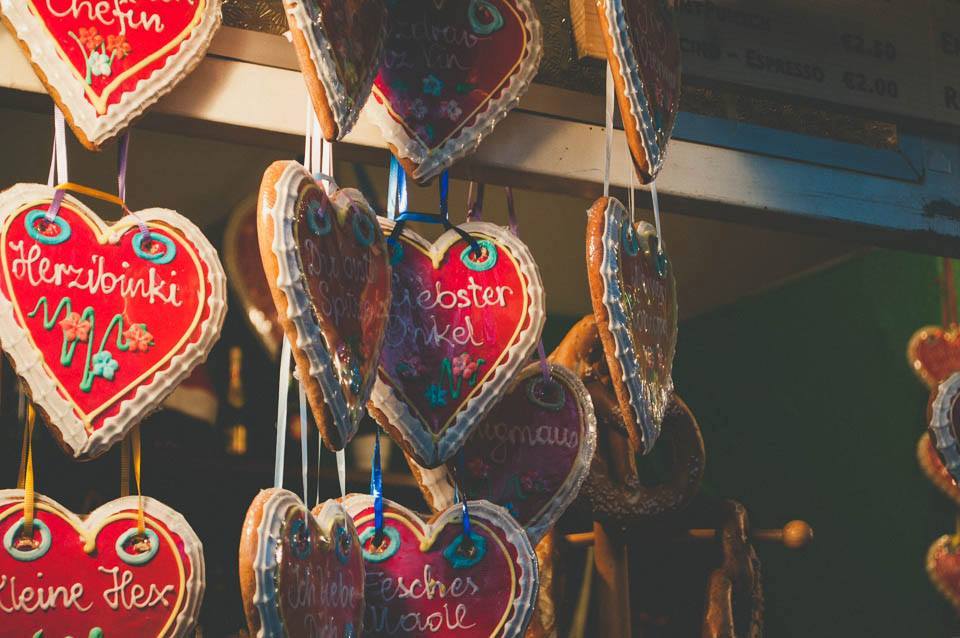 Decorated cookie hearts, emblazoned with various names, hang from blue and pink ribbons.
